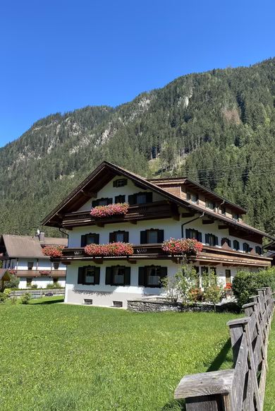 Pension Eberharter in Mayrhofen im Zillertal mit blumengeschmückten Balkonen und Blick auf die Zillertaler Alpen.