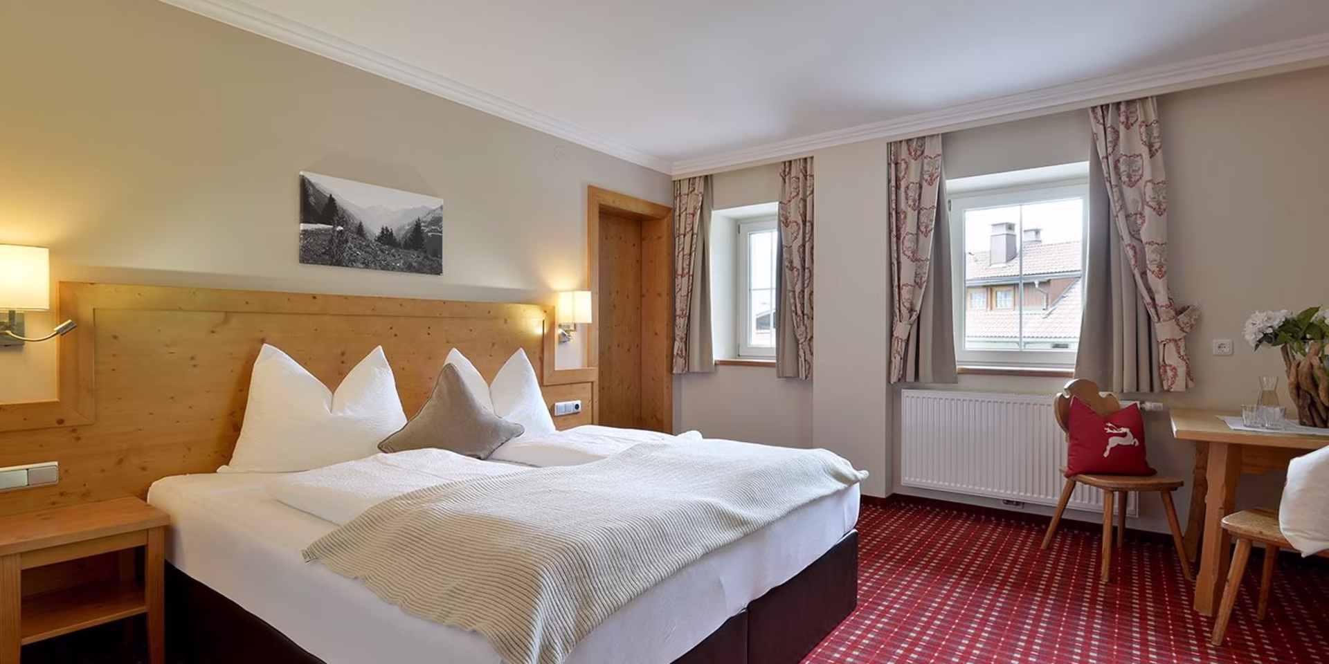 Appartement 4 Schlafzimmer | Pension Eberharter Mayrhofen Zillertal Gemütliches Schlafzimmer im Appartement 4 der Pension Eberharter in Mayrhofen mit Doppelbett, rotem Teppich und Sitzgelegenheit.