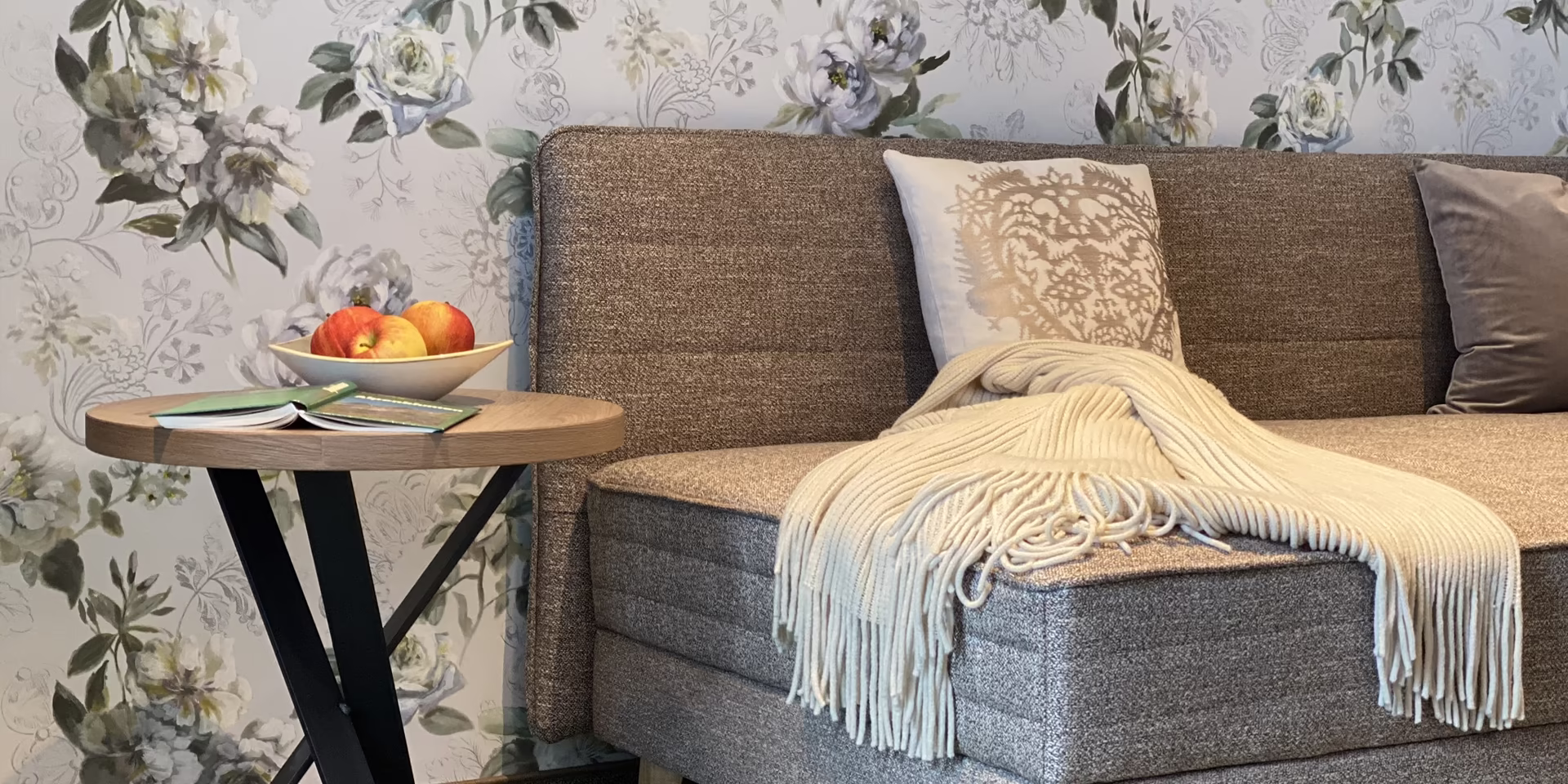 Gemütlicher Wohnbereich im Appartement 5 der Pension Eberharter in Mayrhofen mit Couch, Decke und Apfelschale auf Beistelltisch.